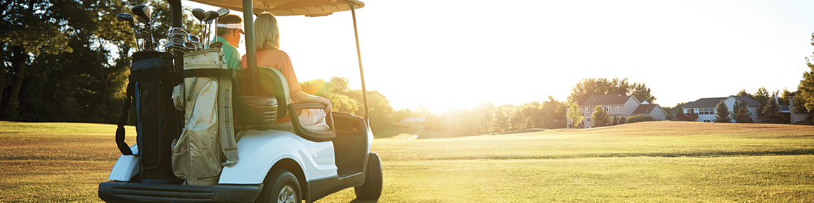 The back of a golf cart riding across the fairway with clubs on the nacl